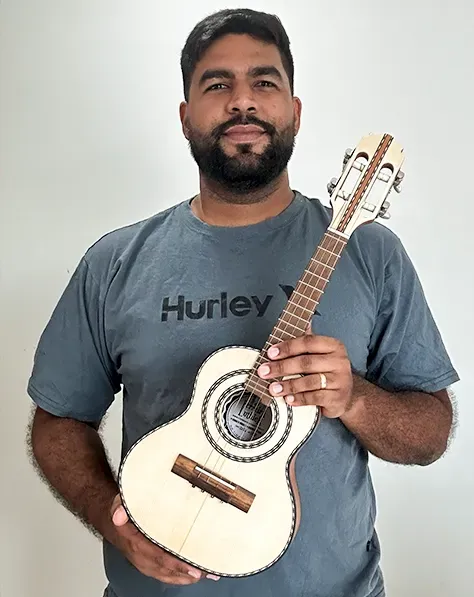Ferreira Luthier segurando um cavaquinho feito por ele